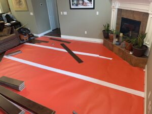 Wood flooring installation in progress with underlayment and planks laid out in a living room by Guzmanremodeling LlC in Renton, WA.