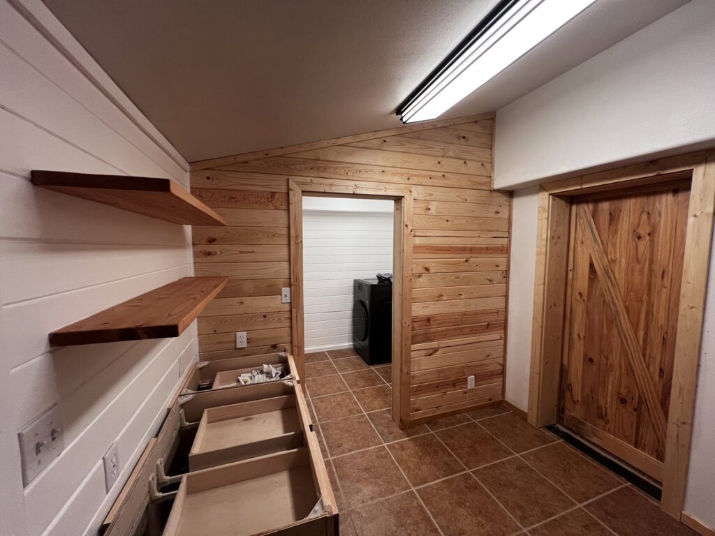 Room under construction with wood paneling, floating shelves, and new door installation by Iron Horse Handyman Services LLC in Laramie, WY.