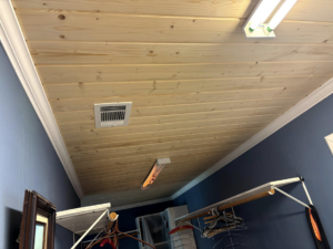A newly installed wood plank ceiling featuring an air vent and modern lighting by Verkler Development LLC in Lake Charles, LA.