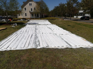 Wood planks laid out on a tarp, prepped for painting or treatment by Bernardo Buildings Inc in Virginia Beach, VA.