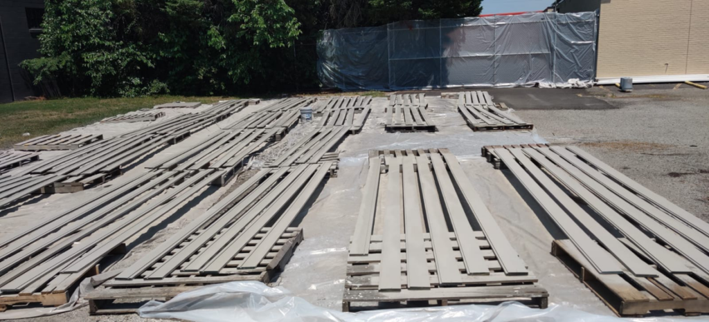 Wood planks laid out on pallets and tarps, prepped for painting by Bernardo Buildings Inc in Virginia Beach, VA.