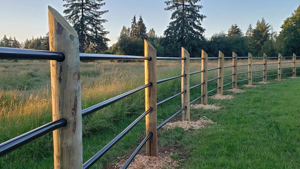 A newly installed wood post and black metal rail fence in a field by J & M Fence Co. in Vancouver, WA.