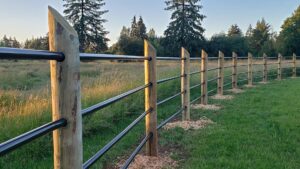 A newly installed wood post and black metal rail fence in a field by J & M Fence Co. in Vancouver, WA.