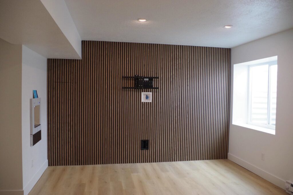 A room featuring a newly installed wood-slat accent wall and a mounted television bracket, completed by Devco Construction LLC in West Valley City, UT