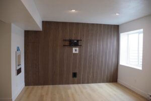 A room featuring a newly installed wood-slat accent wall and a mounted television bracket, completed by Devco Construction LLC in West Valley City, UT