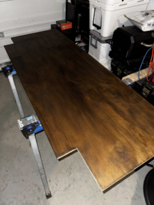 A wooden board being stained on sawhorses for a carpentry project by Premier Handyman Services in Lexington, KY.