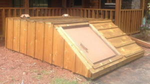 A newly installed wooden above-ground storm shelter in a backyard by Taylor Storm Shelters in Stillwater, OK.