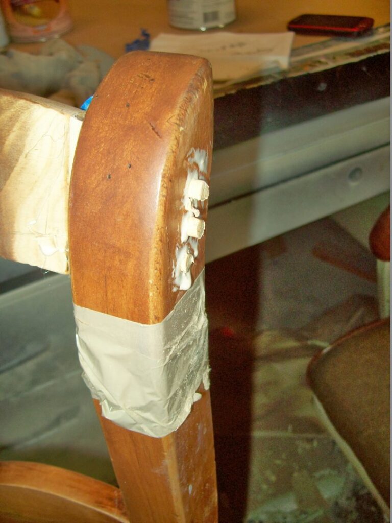 Close-up of a wooden chair leg being repaired with glue and tape by Custom Carpentry Service in Knoxville, TN.