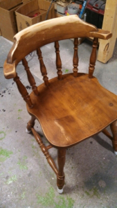 A wooden chair in the process of being refinished, showcasing the before stage by Symphonic Painting in Oshkosh, WI.