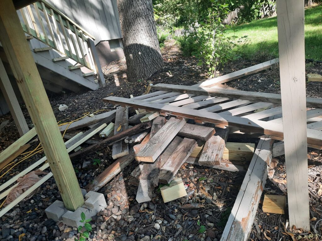 A pile of wooden debris and planks under a deck, ready for removal by Sunshine junk removal LLC in Lake City, MN.