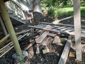 A pile of wooden debris and planks under a deck, ready for removal by Sunshine junk removal LLC in Lake City, MN.