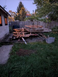 A large pile of wooden debris and pallets in a backyard, ready for removal by Feelin Good Junk Removal & Estate Sales at 1111 Debra Lane.
