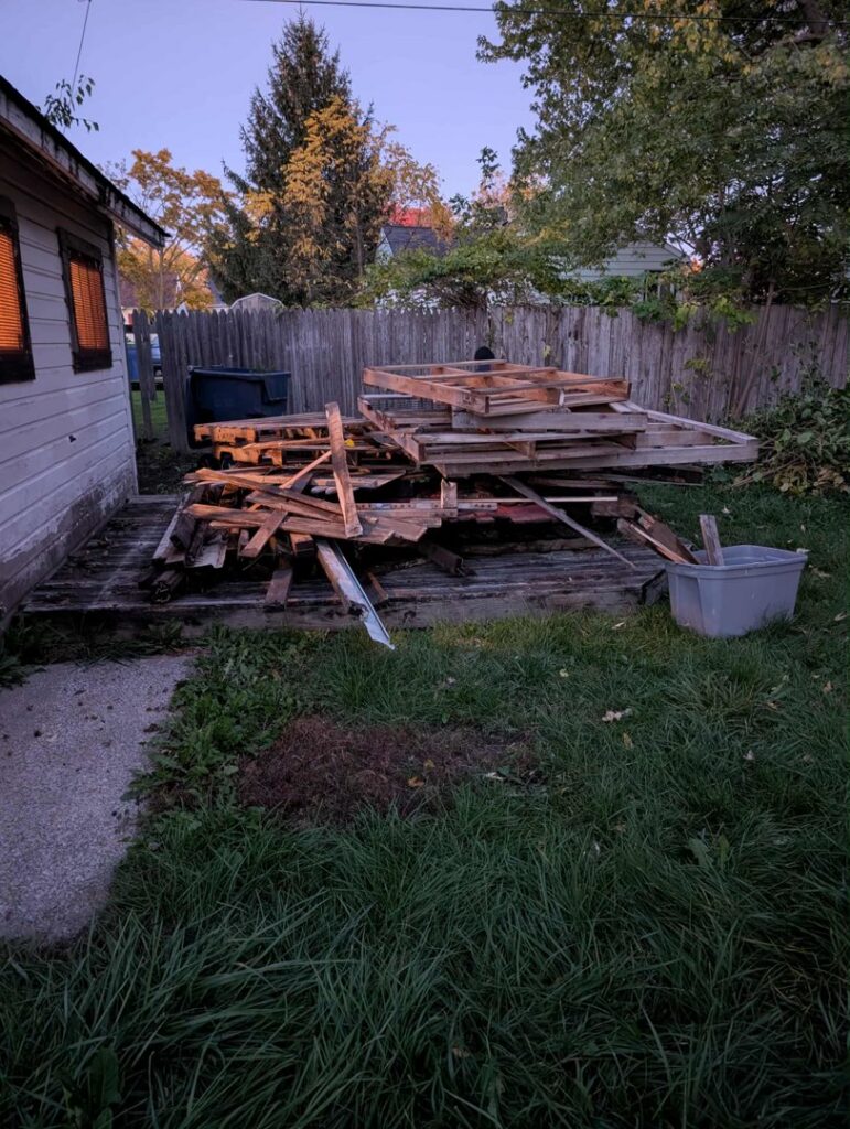 A large pile of wooden debris and pallets in a backyard, ready for removal by Feelin Good Junk Removal & Estate Sales at 1111 Debra Lane.