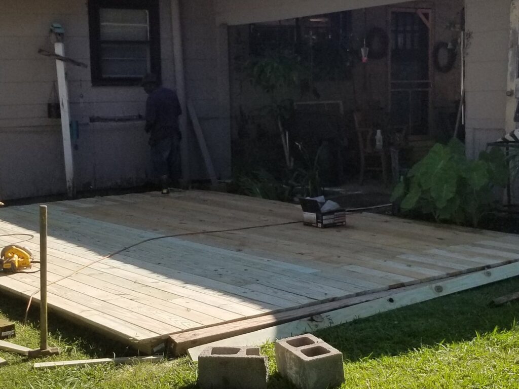 A wooden deck under construction with a worker in the background, showcasing a project by Lee's Handyman Service LLC in Oxford, MS.