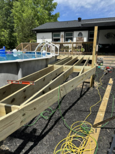 Wooden deck framing under construction next to an above-ground pool, a handyman project by Fence&Wash in Rock Hill, SC.