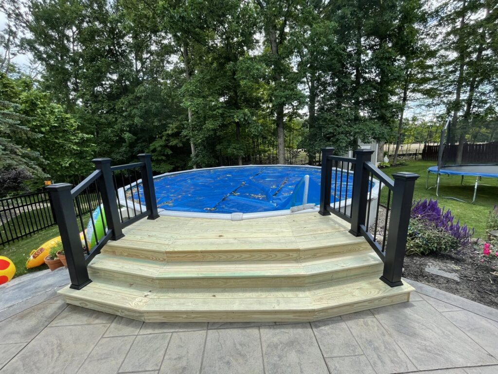 A custom-built wooden deck with steps providing access to an above-ground pool by Inspired Renovation & Hardscape's in Lorain, OH.