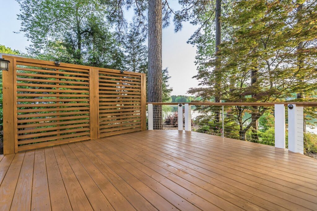 A wooden deck featuring a slatted privacy screen and modern cable railings by Constructive Design Group in Raleigh, NC