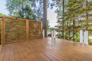 A wooden deck featuring a slatted privacy screen and modern cable railings by Constructive Design Group in Raleigh, NC