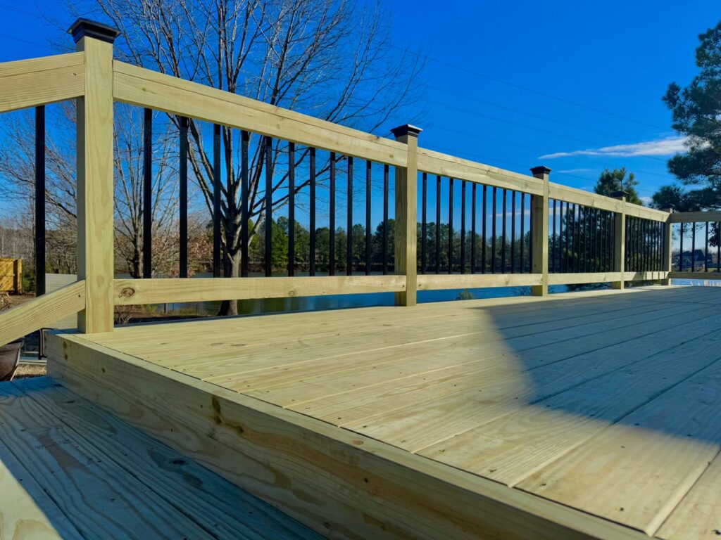Detail of a newly installed wooden deck railing with black balusters by BOS HOME Exterior Services in Virginia Beach, VA