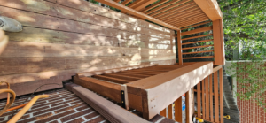 Close-up of a wooden deck railing and floor, showing repair or construction work by All Hung Up LLC in Littleton, CO.