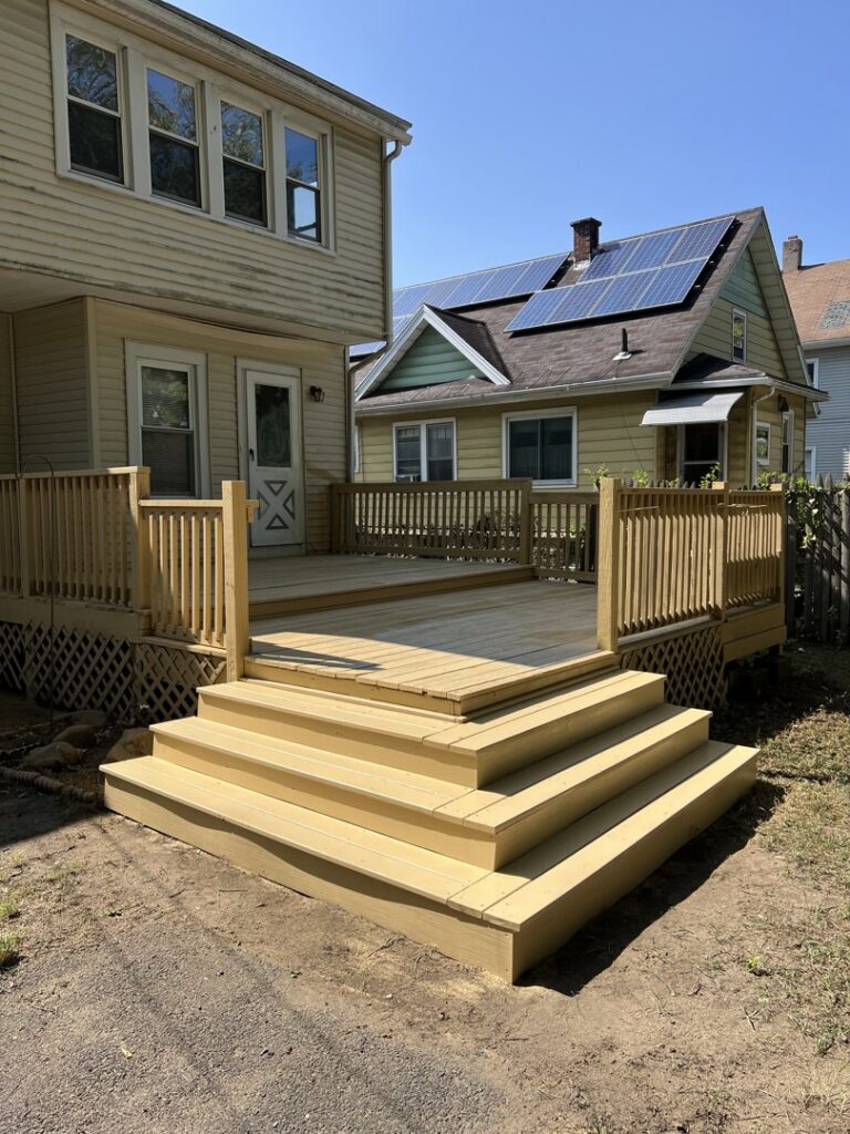 A newly installed wooden deck with wide stairs by TD Estimating Group LLC in Springfield, MA, perfect for backyard enjoyment.