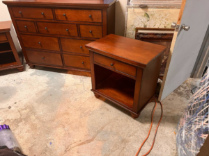 A wooden dresser and matching nightstand on a concrete floor, awaiting general junk removal by Junk2Dump in Sacramento, CA.