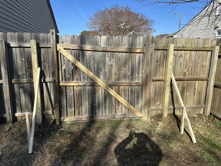 A wooden fence gate with new support posts installed by Jps handyman services,inc in Hampton, VA.