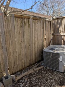 A wooden fence with a section that appears to be a repaired gate or panel, a handyman service by Lula - Reinventing Property Maintenance in Overland Park, KS.
