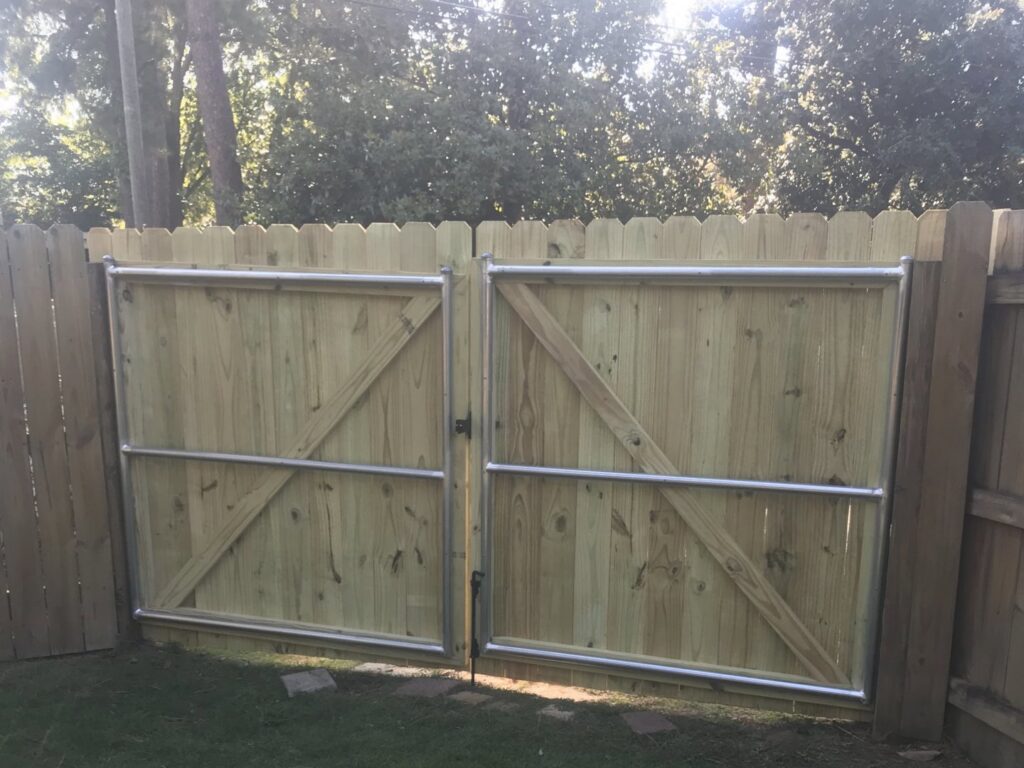 Newly installed wooden fence gates with metal support frames, demonstrating gate installation by Steven's Deck and Fence Staining Columbus, GA.