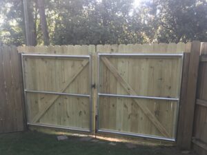 Newly installed wooden fence gates with metal support frames, demonstrating gate installation by Steven's Deck and Fence Staining Columbus, GA.