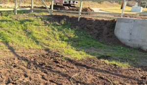 Wooden fence installation in progress, showing new posts and an excavator, by MHK Yard & Gravel in Manhattan, KS