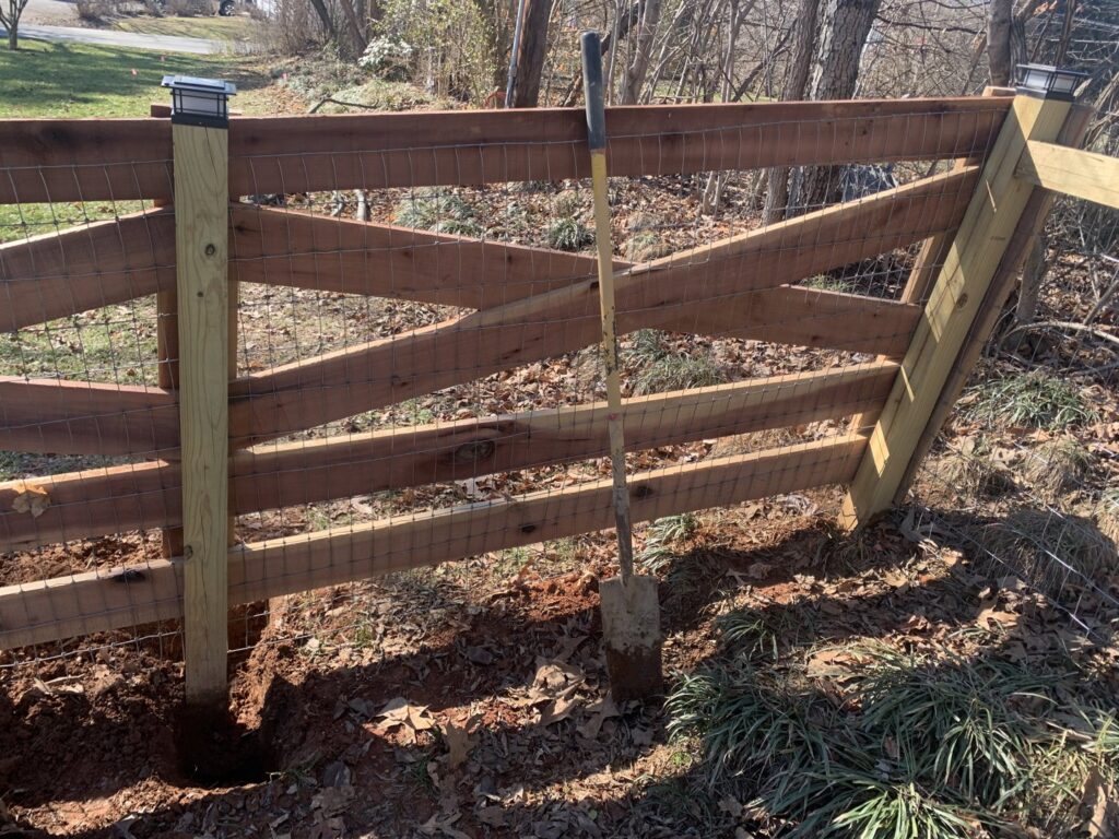 A wooden fence being installed or repaired with a shovel in the ground by Rainscapes in Louisville, TN.