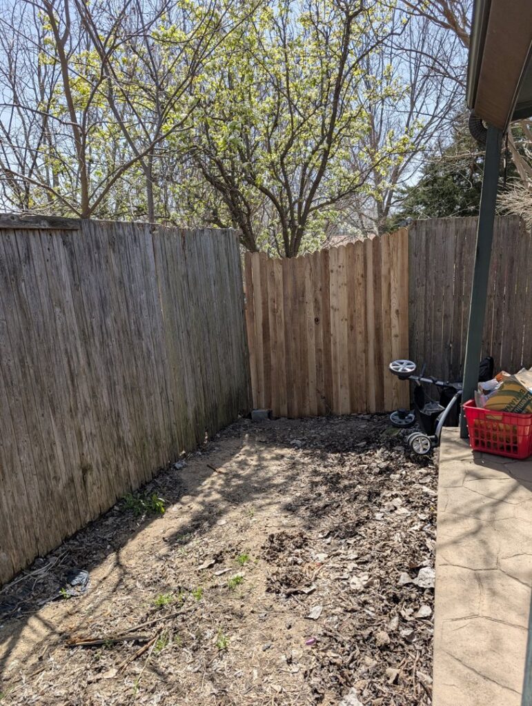 A wooden fence with a newly replaced section of lighter wood panels, a handyman service by Lula - Reinventing Property Maintenance in Overland Park, KS.