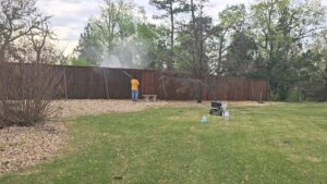 A person performing professional pressure washing on a wooden fence by Acosta Painting LLC in Jonesboro, AR.