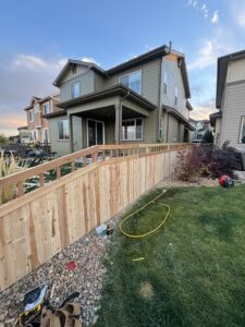 Newly installed wooden fence with a top railing by Blue Collar Service Pros in Aurora, CO, with tools on the ground.
