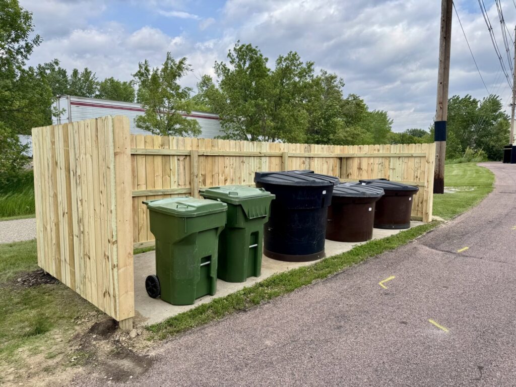 A newly built wooden fence enclosing trash bins, constructed by Northeast SD Handyman in Watertown, SD.