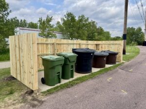 A newly built wooden fence enclosing trash bins, constructed by Northeast SD Handyman in Watertown, SD.