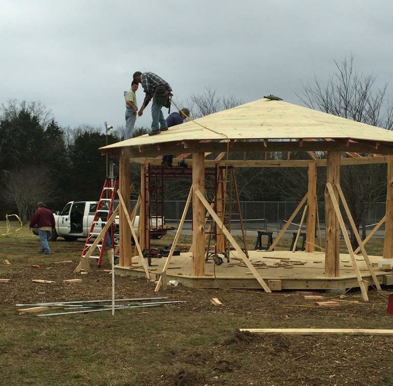 Workers constructing a wooden gazebo, demonstrating outdoor building services by Chicago Service Source Inc in Chicago, IL