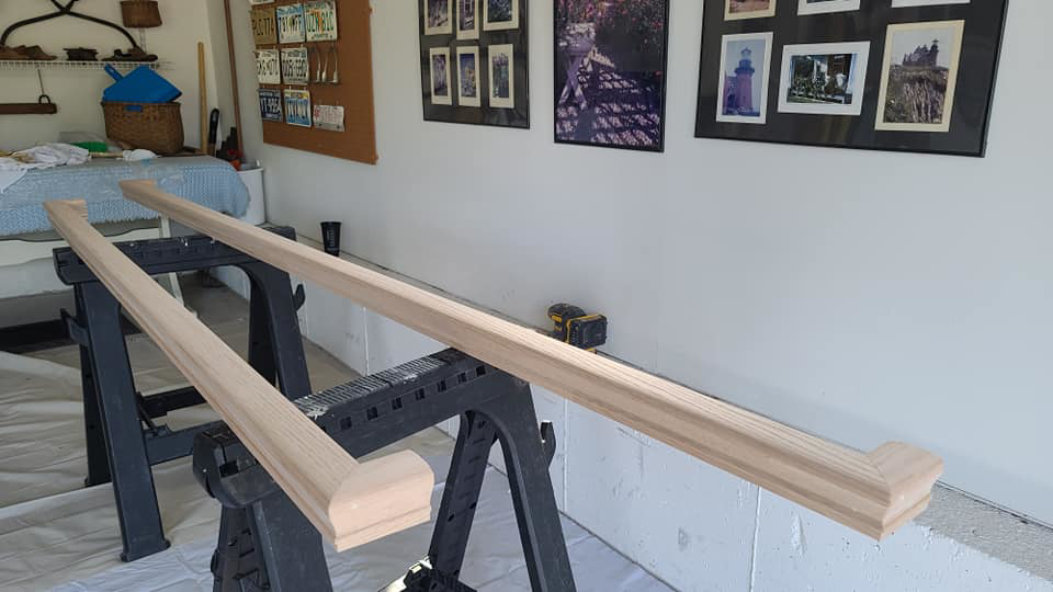 Two wooden handrails resting on sawhorses, prepared for finishing by Small Jobs Well Done in Avon, CT.