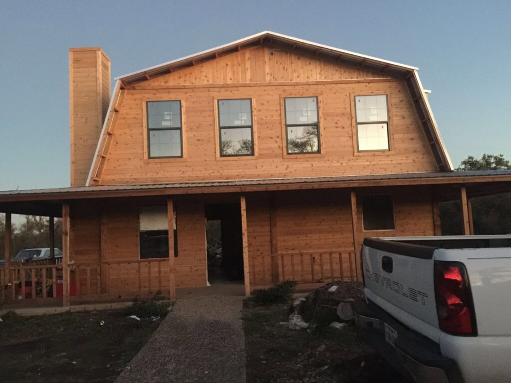 The exterior of a large wooden house under construction, showcasing new siding and windows by Savala's Remodeling Services in Austin, TX.