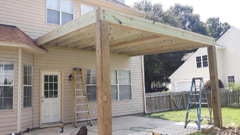 A wooden pergola under construction, attached to a house by Signature Deck & Pergola in Virginia Beach, VA
