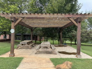 A newly installed wooden pergola with picnic tables by Oklahoma Painting & Construction in Oklahoma City, OK.
