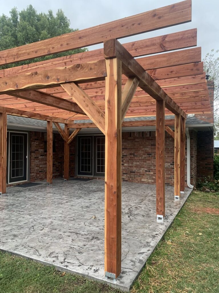 A newly constructed wooden pergola over a stamped concrete patio by Holaway Custom Builds in Fayetteville, AR.