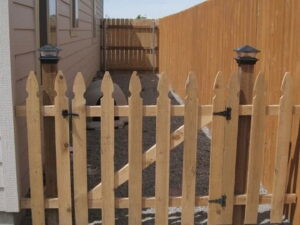 A newly installed wooden picket fence with a gate, demonstrating fence services by Steven's Deck and Fence Staining Columbus, GA.