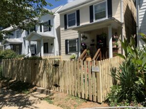 A wooden picket fence with a gate installed in a front yard by Premier Fence Company in Glen Allen, VA.