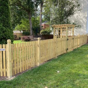 A newly installed wooden picket fence with a gate and decorative pergola by Minors Fences in Ashland, VA.