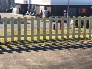 A newly installed wooden picket fence in front of a commercial property by Fence & More in Elizabethtown, KY