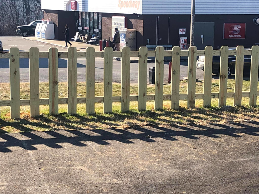 A newly installed wooden picket fence in front of a commercial property by Fence & More in Elizabethtown, KY