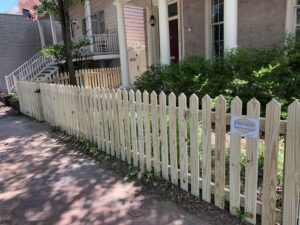 A wooden picket fence installed along a sidewalk in front of a house by Premier Fence Company in Glen Allen, VA.