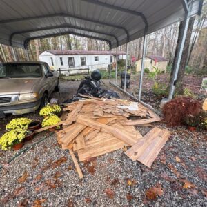 Wooden planks and black trash bags piled under a carport for junk removal by Veterans Easy Trash: Atlanta in Atlanta, GA.